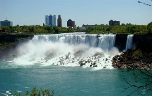 A large waterfall with a city in the background

Description automatically generated with medium confidence